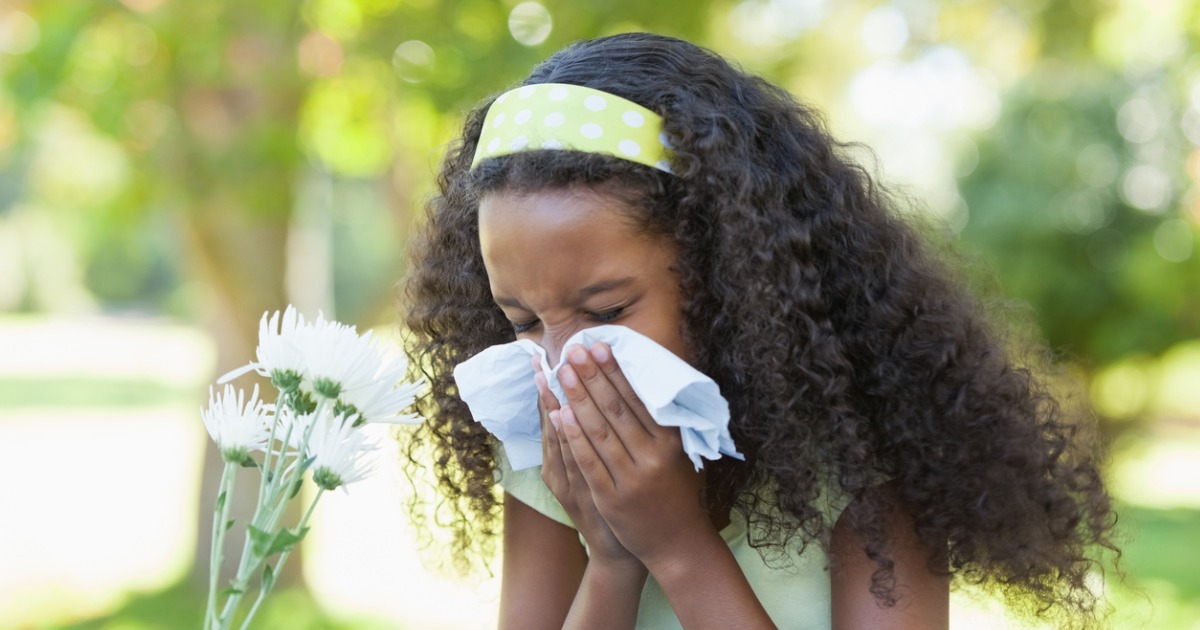 A young girl blows her nose