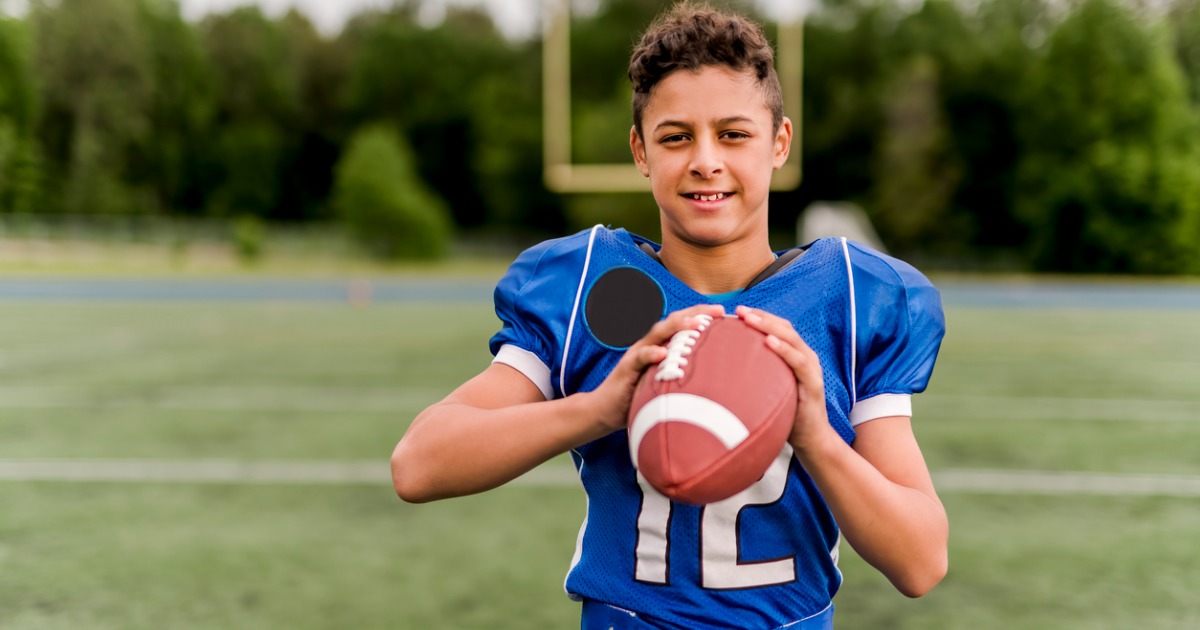 Young boy in a football jersey holding a football