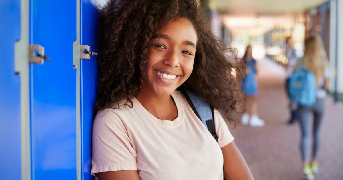 A young girl smiles and leans against her locker