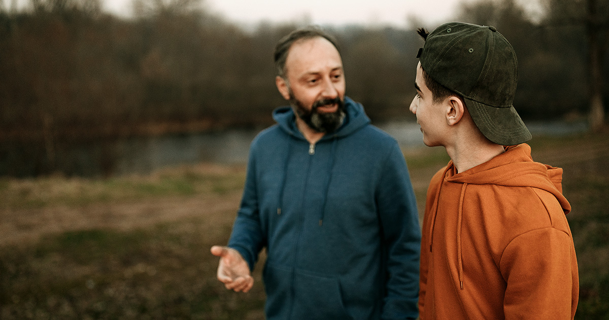 A dad talking with his son outside