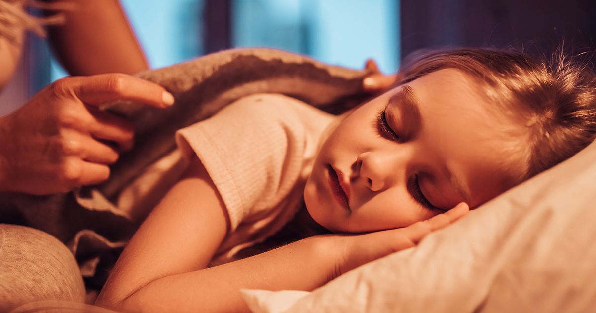 Young girl being tucked into bed