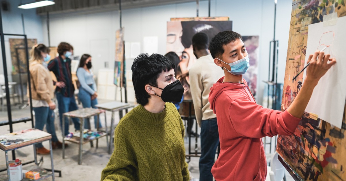 Two high schoolers work on a painting