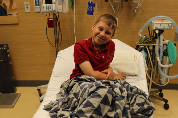 happy child waiting patiently on hospital bed