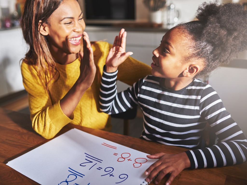 Mom and school-aged daughter high-fiving during math assignment