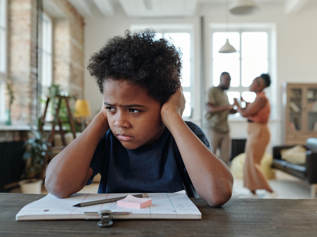 School boy stressed, sitting at desk, doing homework