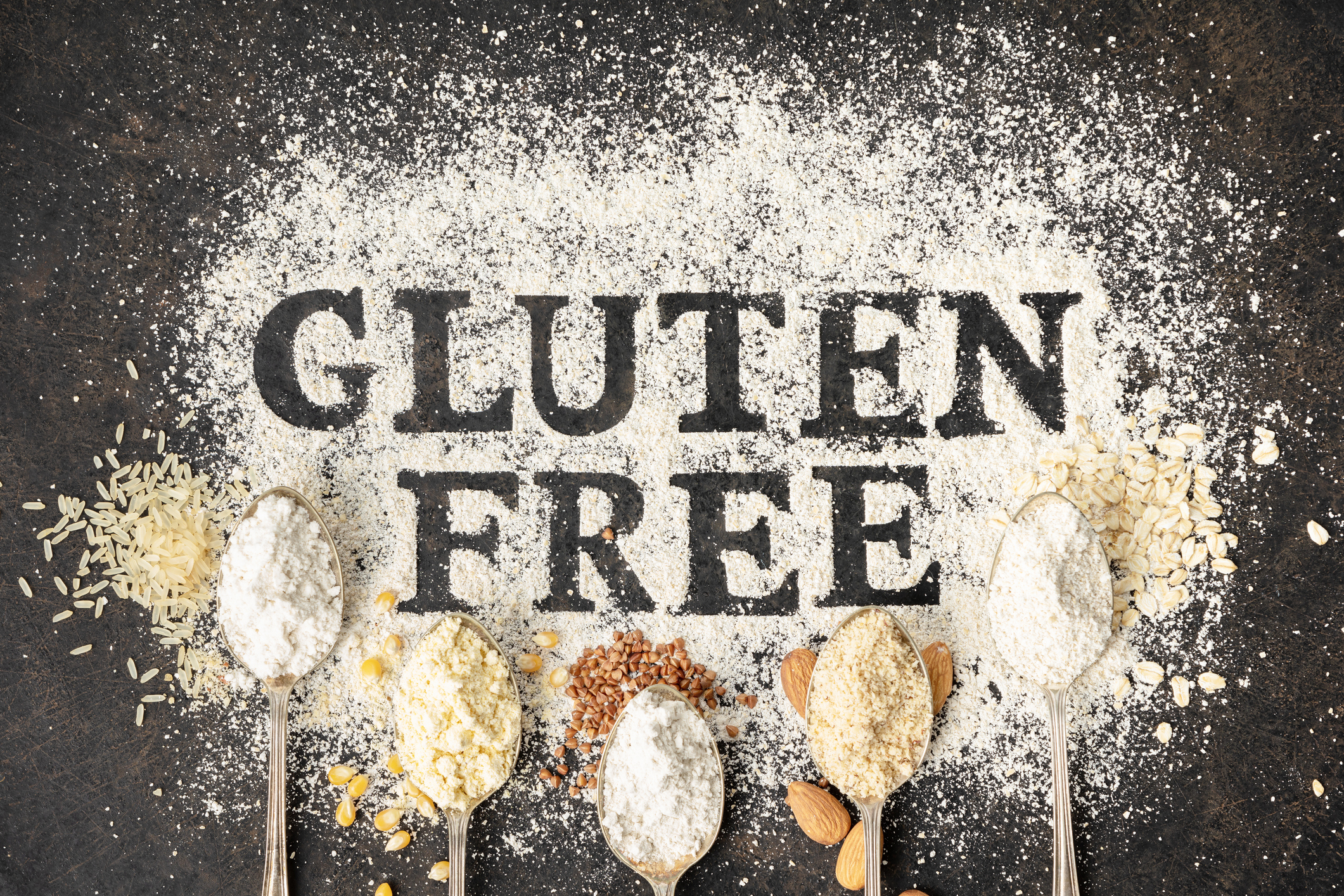 Gluten Free written on table of flour surrounded by spoons