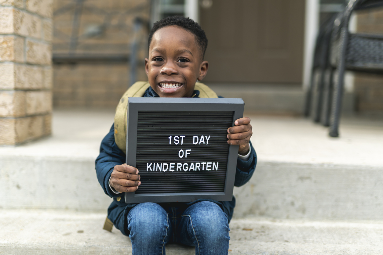 Child on his first day of school holding sign