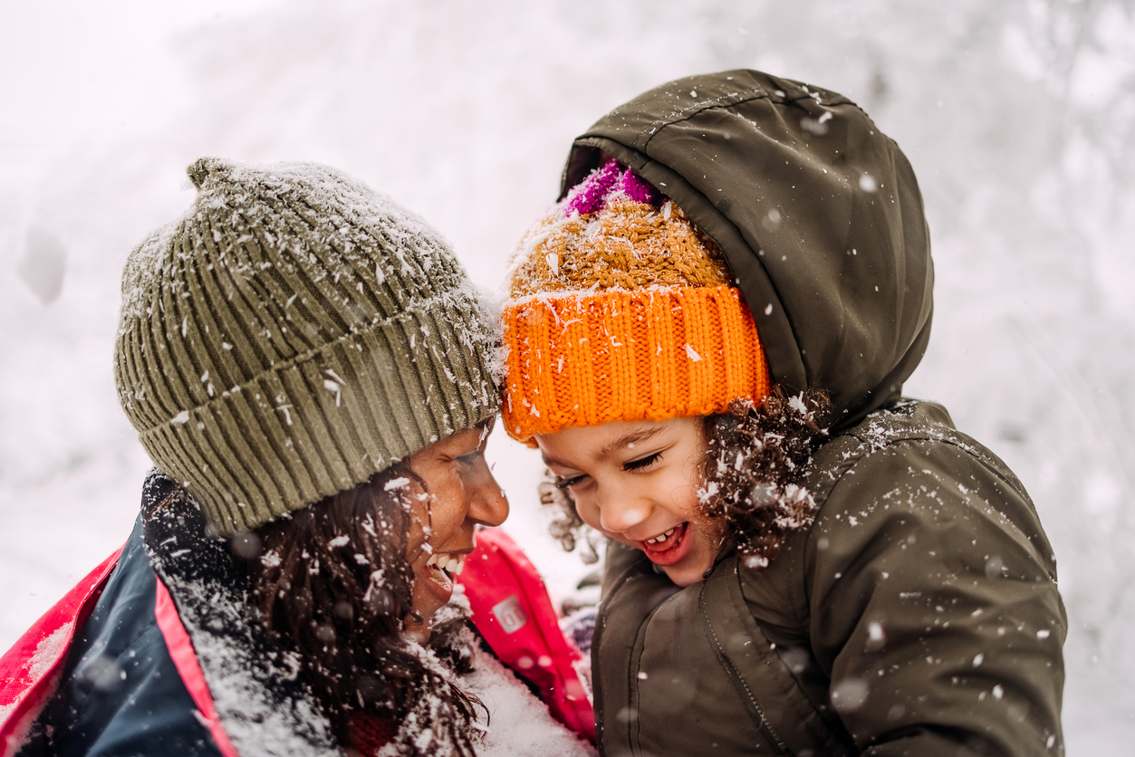 A mom and daughter playing in the snow together