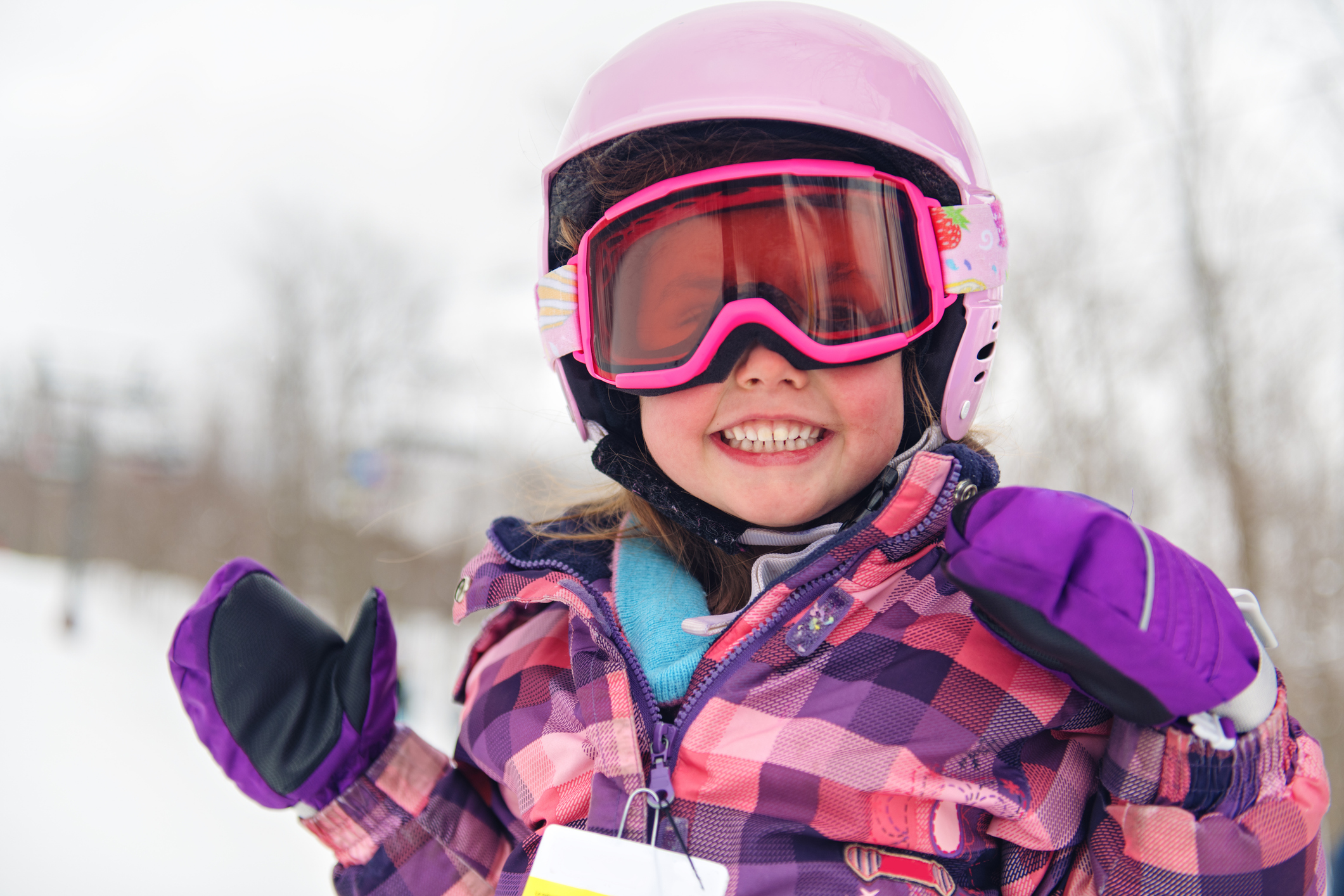 A child playing in the snow wearing ski goggles and ski helmet. 