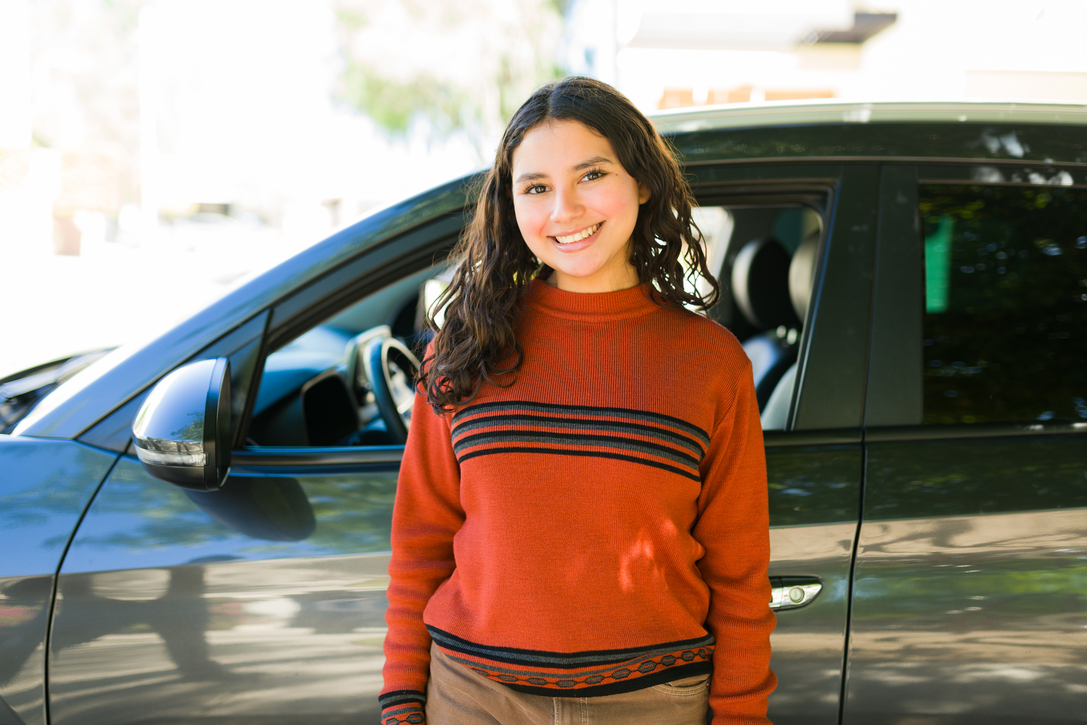 Teen driver standing in front of car