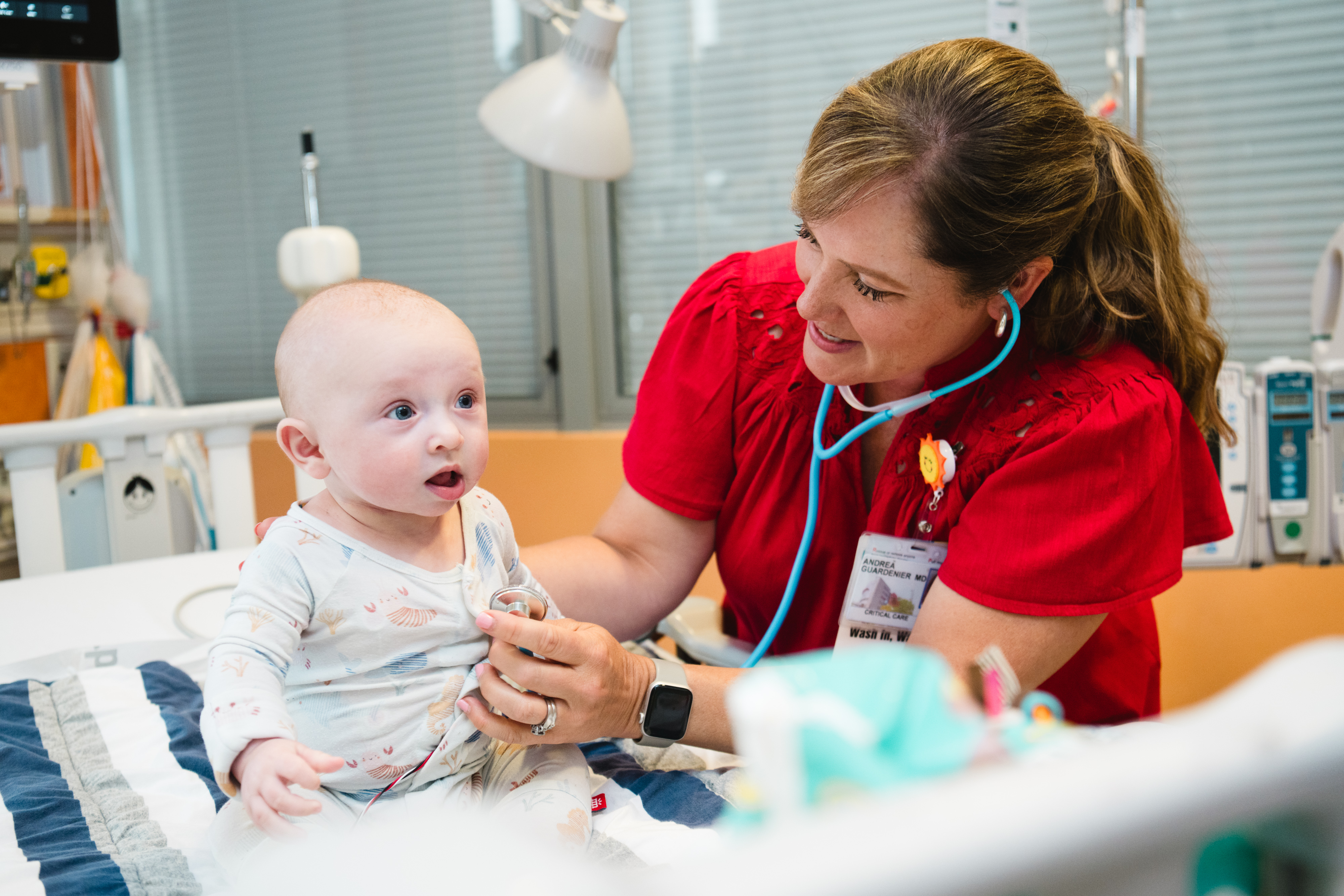 A baby inpatient in the cardiac ICU is examined by his doctor.