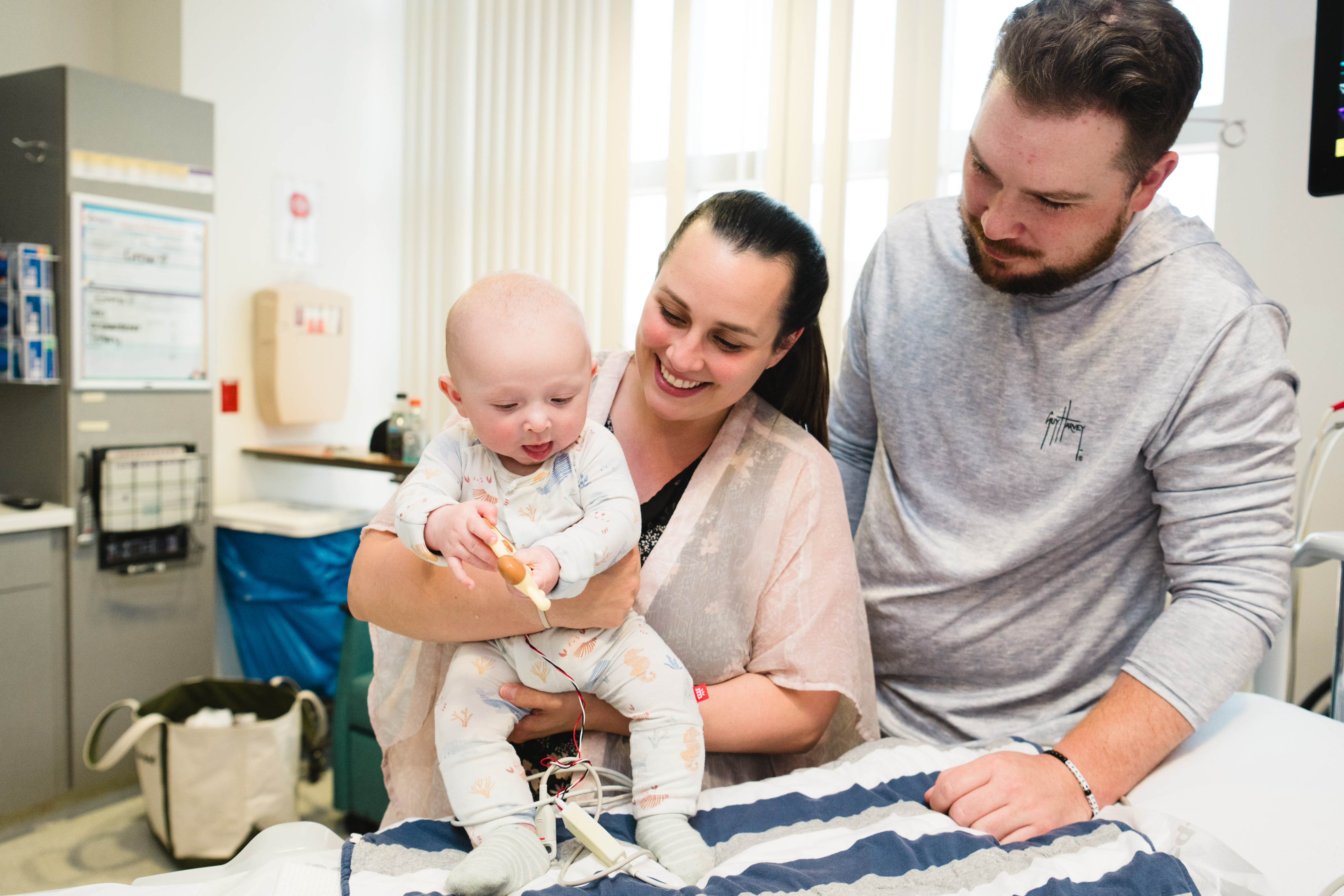 A baby inpatient in the cardiac ICU is examined by his doctor.