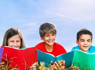 Kids reading books laying the grass