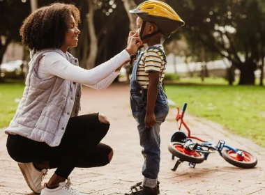 Mom fastening a bike helmet on a child