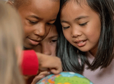 Groups of kids looking at a globe