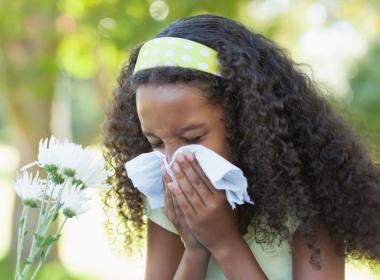 A young girl blows her nose
