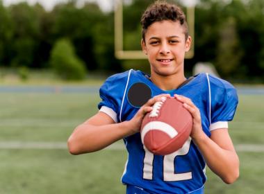 Young boy in a football jersey holding a football