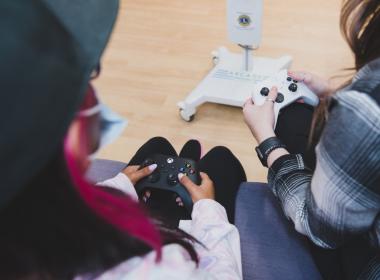 Two young women hold video game controllers
