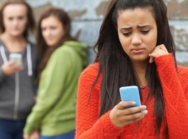 A young teen looks at her phone sadly