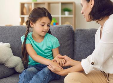 Mother sitting with daughter holding her hands