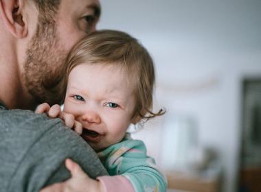 A dad holds his crying toddler