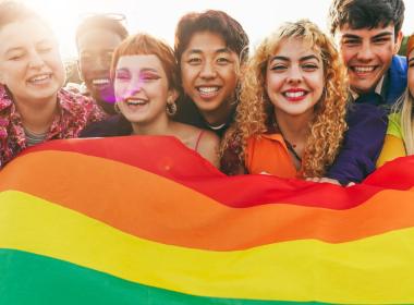 A group of friends hold a pride flag
