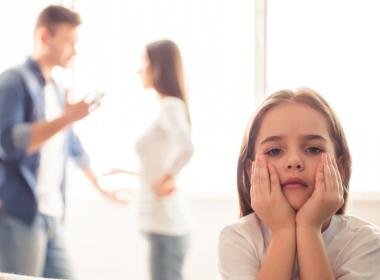Sad child, parents arguing in the background