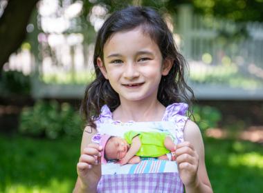 Claire holding a baby photo of herself