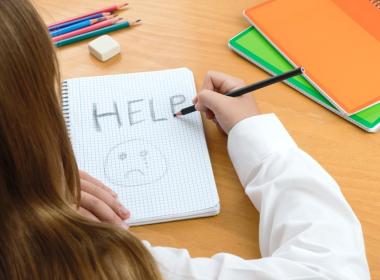 Child writing "HELP"