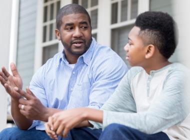 Attentive school-aged boy, listening to father during conversation