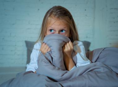 Child startled, awake in bed.