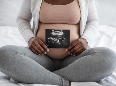 Black Woman holding sonogram. 