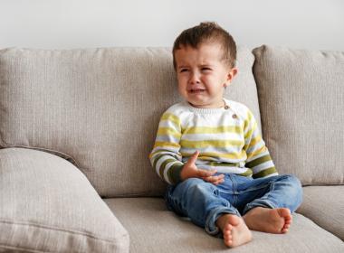 Toddler boy crying on couch