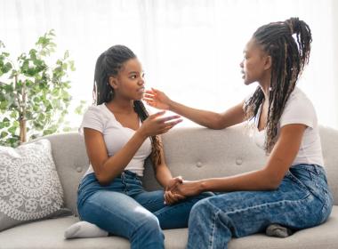 mother and teenage daughter sitting on couch talking maybe about breast reduction surgery