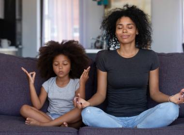 Mom and daughter meditating on couch, practicing calming exercises