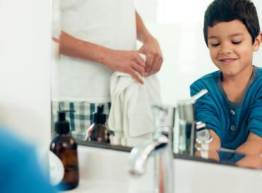 Family, cleaning and boy with hands in sink in bathroom with father and skincare for hygiene at home together