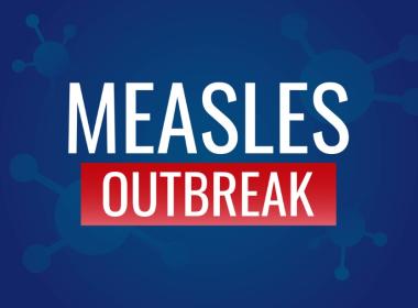 White and red text Measles Outbreak against blue background