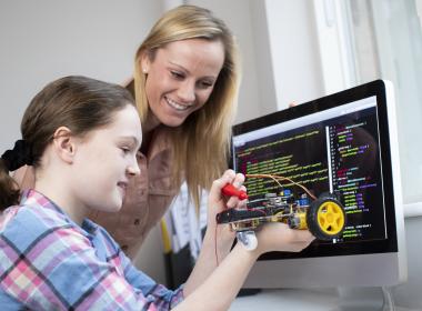 Teacher with middle school aged girl, building robot, mental health tips for caregivers and school staff
