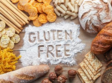 Rice, pastas and breads surrounding a pile of flour in which "gluten free" is written