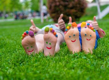 hildren's feet with a pattern of paints smile on the green grass