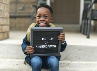 Child on his first day of school holding sign