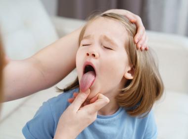 Young girl getting throat checked, tongue out