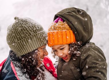 A mom and daughter playing in the snow together