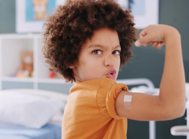 Young boy proudly lifts arm after receiving vaccine