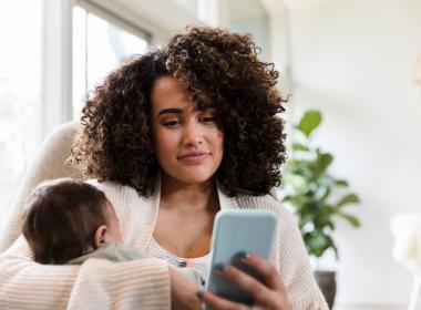 Mom holding baby and looking at cell phone