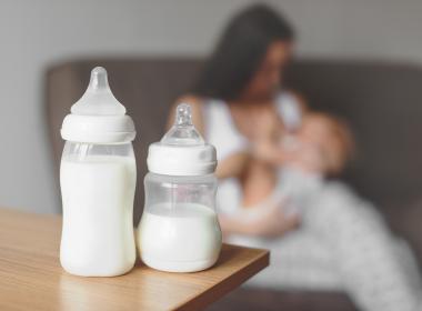 Bottles and a woman breastfeeding in the background