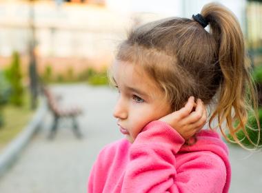 Young girl, around 3, clutching left ear
