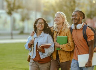 Three students walking on a college campus. 