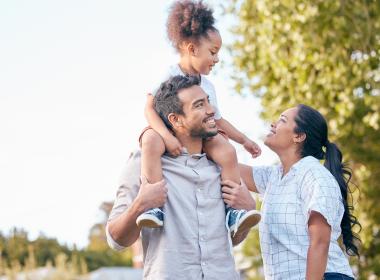 A mom, dad and daughter outside together.