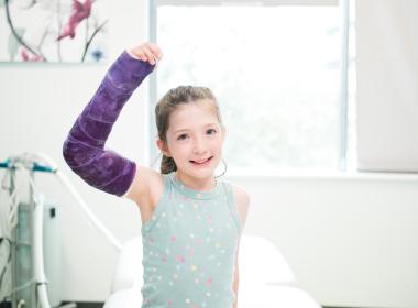 A patient with a cast in orthopedics clinic looks into the camera.